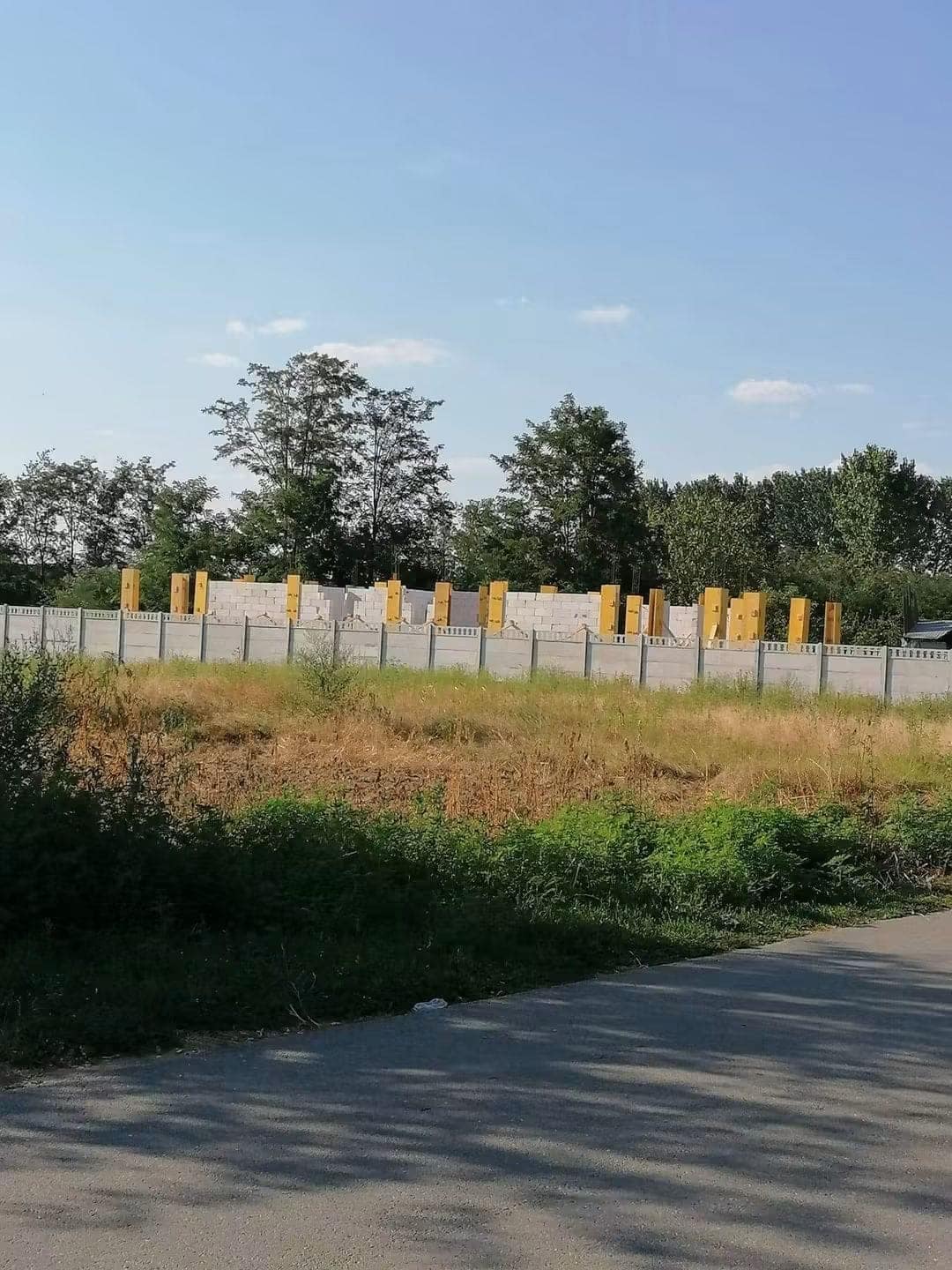 Casă la roșu în ridicare: zidărie pe tot conturul, cu cofrajele galbene ale stâlpilor de beton montate între panourile de zidărie