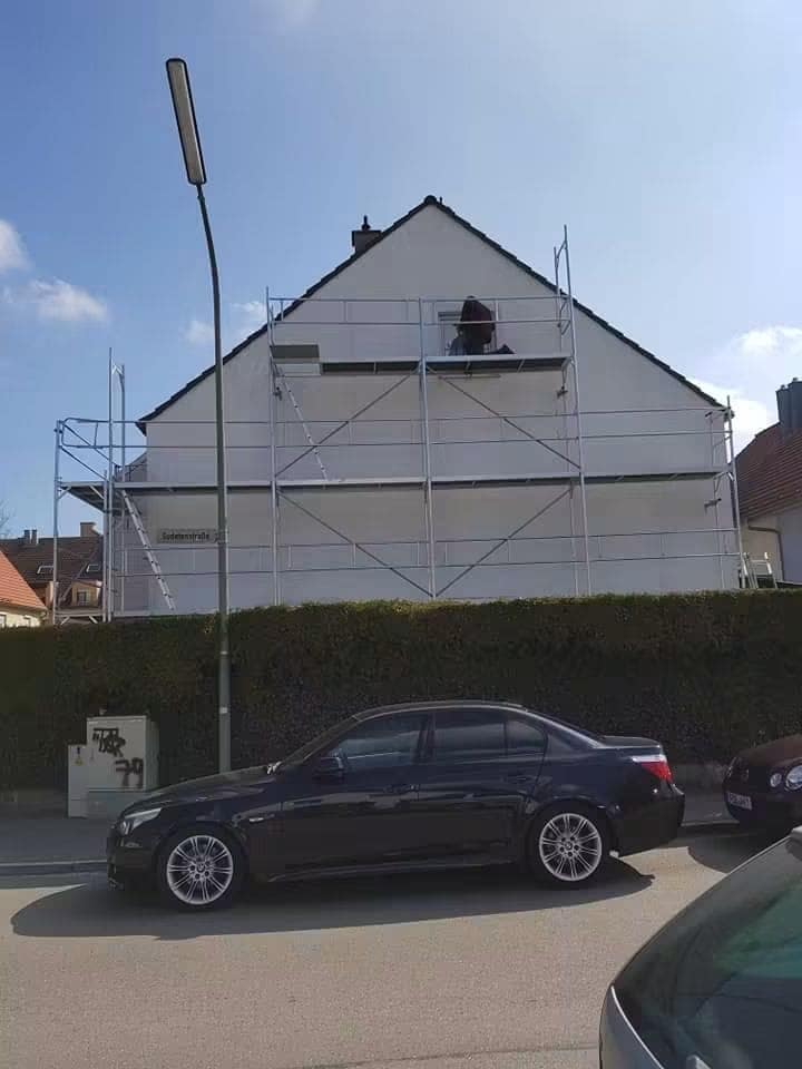 Casa schelată pe toată fațada, cu echipa lucrând la fronton, văzută dinspre stradă