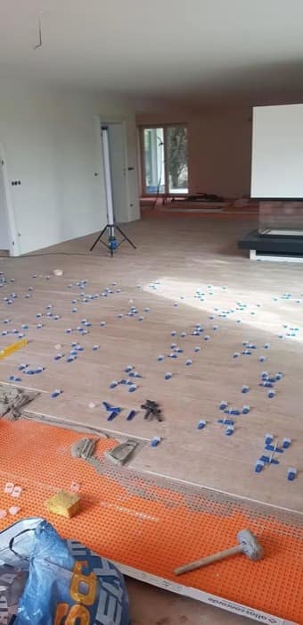 Montaj în curs pe o suprafață deschisă, cu distanțierele lăsate pe rosturi până la priza adezivului