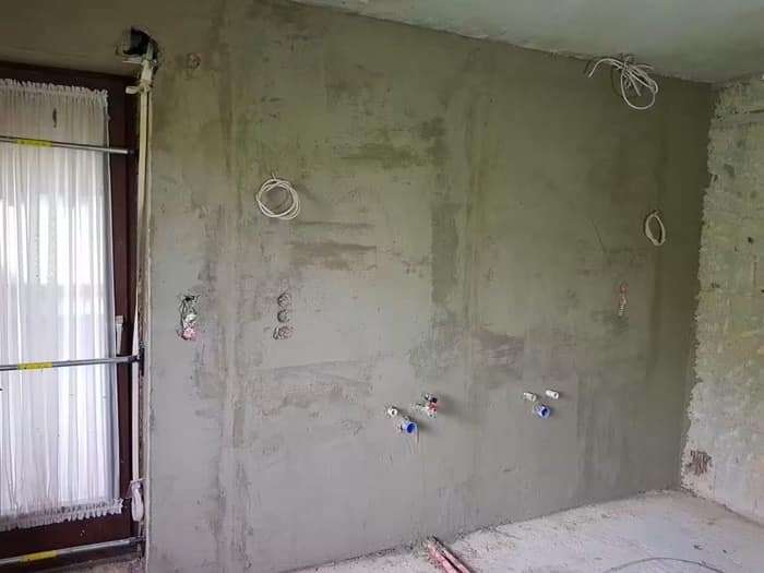 Perete tencuit peste dozele electrice și racordurile sanitare lăsate la vedere pentru montaj
